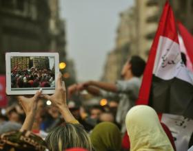 Protesters wave a Egyptian flag as the activities during the Egyptian Revolution are captured on a tablet computer.