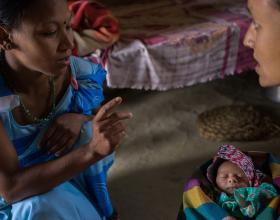 A woman is speaking to another woman holding a baby.