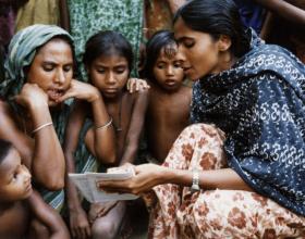 Source - © 1994 Cheryl Groff, Courtesy of Photoshare. A Family Welfare Assistant shares family planning information with villagers in the Trishad District of Bangladesh.