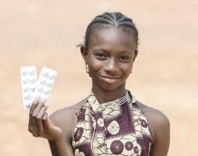 A girl holds up medication. Photo credit- iStock.