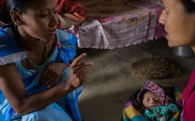 A woman is speaking to another woman holding a baby.