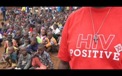 Close up of a man in a crowd wearing a "HIV Positive" t-shirt