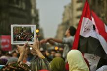 Protesters wave a Egyptian flag as the activities during the Egyptian Revolution are captured on a tablet computer.