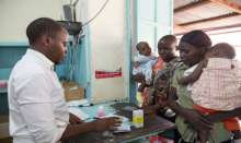 Pharmacist dispenses a prescription to two mothers with young children.