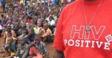 Close up of a man in a crowd wearing a "HIV Positive" t-shirt