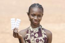 A girl holds up medication. Photo credit- iStock.